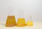 laboratory flasks containing amber cannabis extract at three stages of refinement