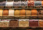 Shelves of a spice market displaying whole spices, ground powders and dried herbs in open glass bins