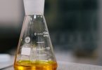 An Erlenmeyer flask of amber liquid on a laboratory bench