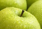 Close-up of green apple skin covered in water droplets